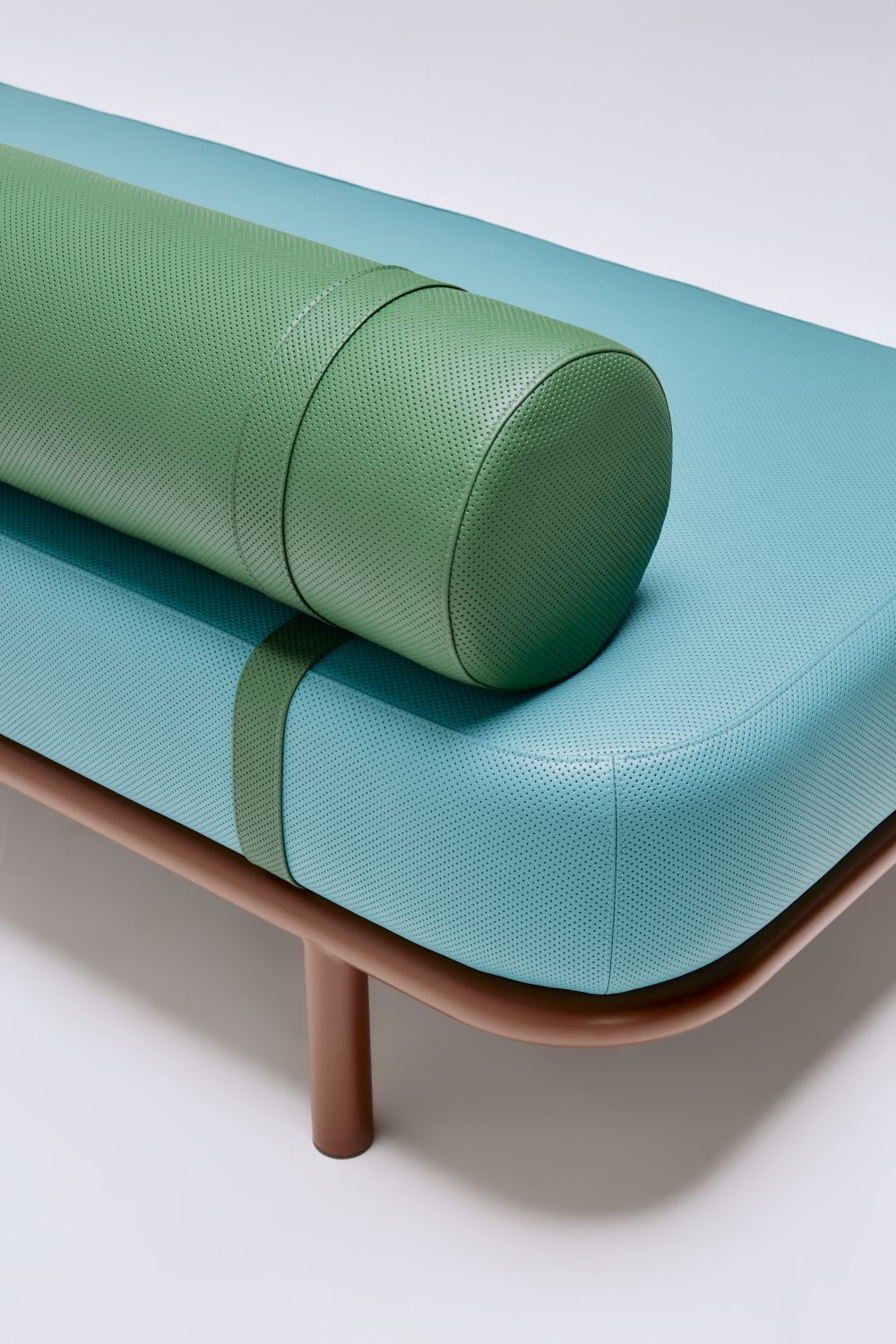graziaco etta ottoman with bolster back in custom green and aqua perforated leather upholstery detail.